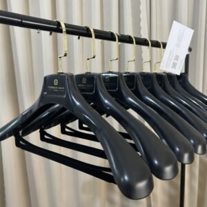 Commercial grade black wood-grain plastic hanger for wholesale use, wide shoulder build with non-slip trouser bar, custom brand logo, chrome swivel hook for apparel retail bulk supply
