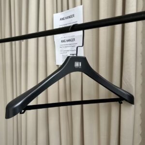 Smooth black bulk plastic suit hanger with trouser bar and black flat hook, custom printed brand logo, hanging on clothing rack for wholesale apparel display