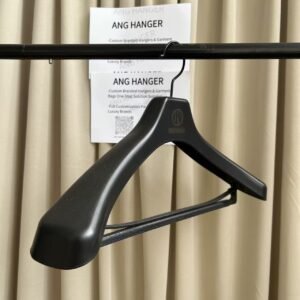 Side view of shiny black extra wide shoulder plastic hanger with thickened shoulder design and non-slip trouser bar, custom engraved logo, for wholesale apparel retail display