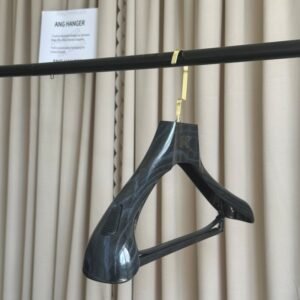 Black imitating wood plastic suit hanger with trouser bar and gold metal hook, custom brand logo on wide shoulder, hanging on clothing rack for wholesale apparel display