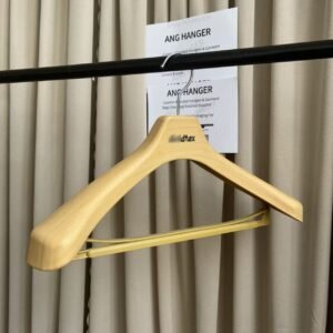 Natural wood finish plastic suit hanger with trouser bar and custom printed logo, hanging on clothing rack for apparel retail display