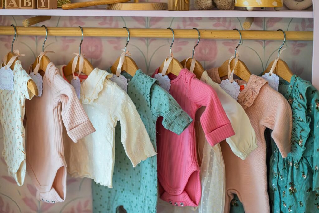 Wooden wholesale baby hangers displaying newborn and toddler clothes in a baby clothing boutique