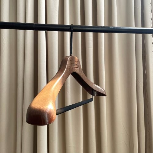 Walnut wood-grain plastic suit hanger with custom logo plate and non-slip pant bar for clothing brand displays
